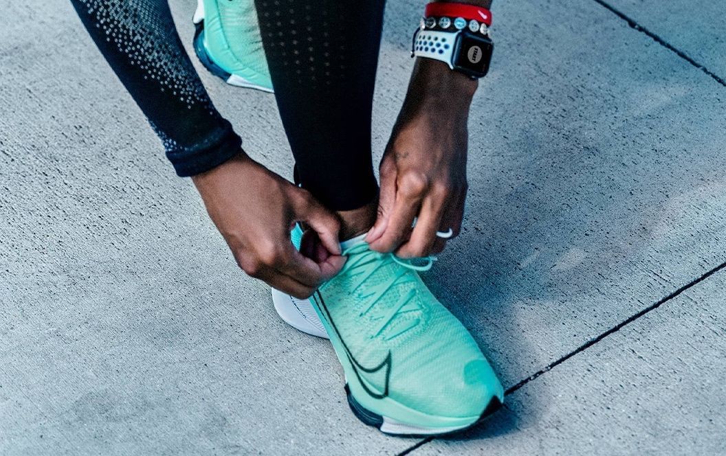 Femme qui refait le lacet de sa chaussure de running Nike